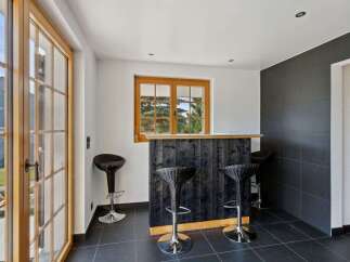 Step into this inviting space featuring a rustic wooden bar with sleek black paneling, perfect for entertaining.