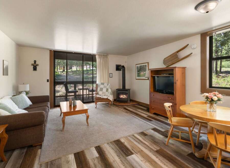 Cozy living room featuring a comfortable brown sofa, a wood-burning stove for warmth, and a dining area perfect for intimate meals.