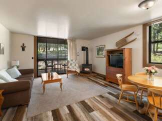 Cozy living room featuring a comfortable brown sofa, a wood-burning stove for warmth, and a dining area perfect for intimate meals.