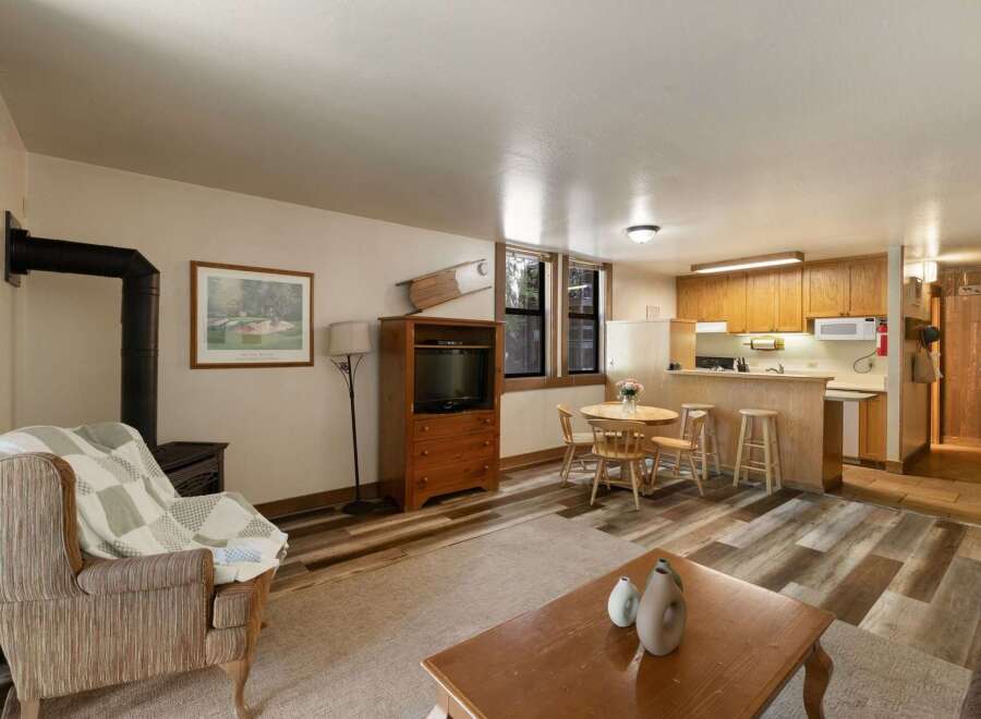 Cozy living space featuring a comfortable armchair with a checkered blanket, a wood-burning stove, and a rustic wooden entertainment center.