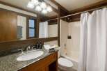 This rustic bathroom features a granite-topped vanity with a undermount sink and a wooden cabinet below.