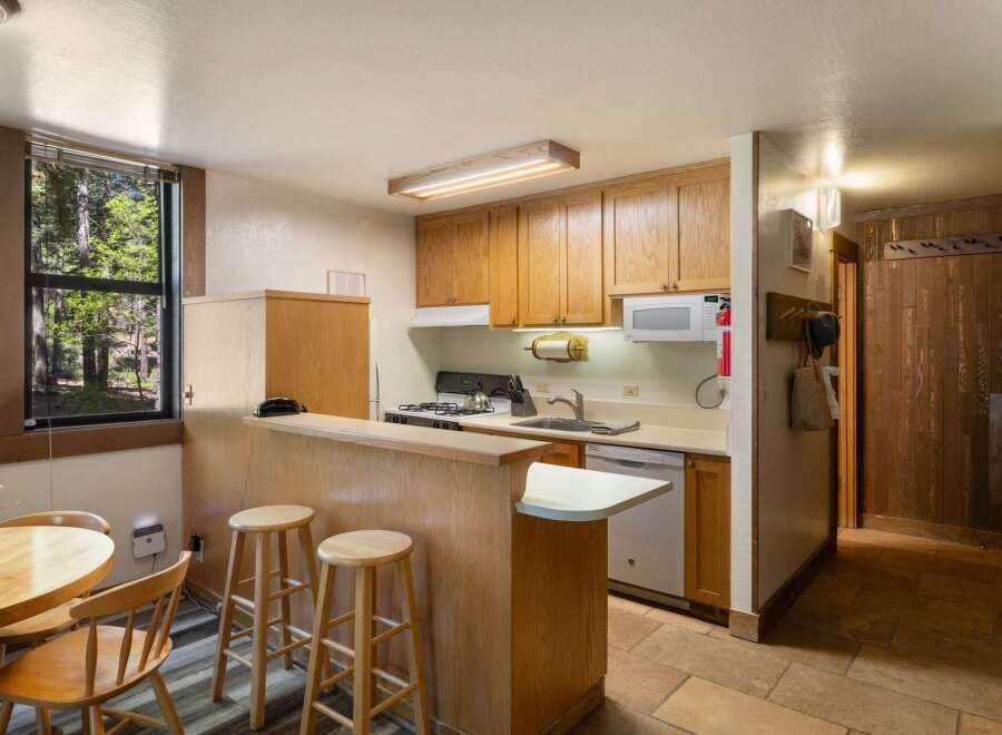 This charming kitchen features ample wooden cabinetry and a convenient breakfast bar with stools, perfect for casual dining.