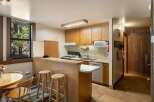 This charming kitchen features ample wooden cabinetry and a convenient breakfast bar with stools, perfect for casual dining.