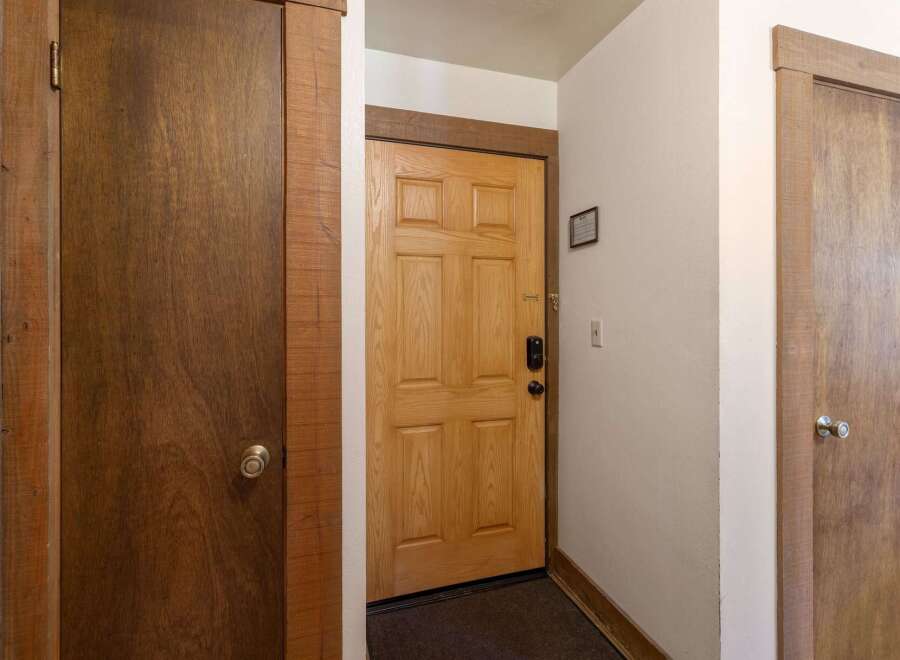 Step into this inviting entryway featuring a warm wooden door with a modern black lock, offering a secure and stylish welcome.