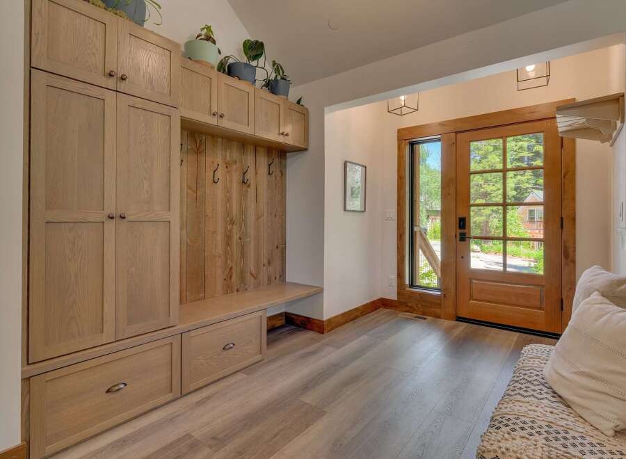 Step into this charming entryway featuring a custom built-in mudroom with ample storage and a cozy bench.