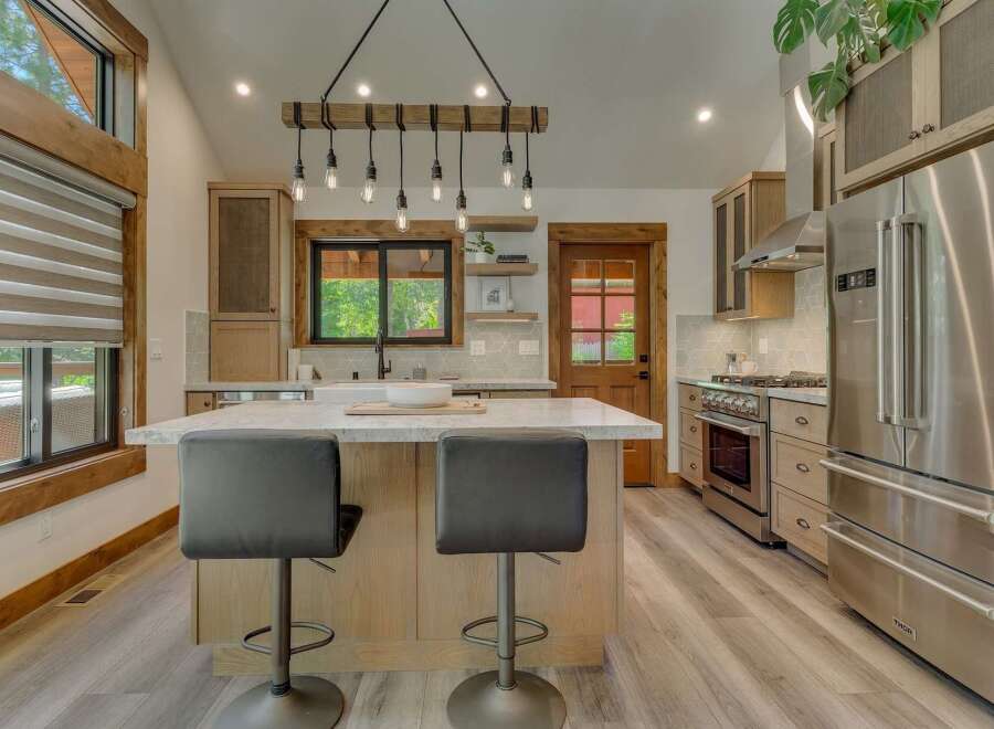 Experience modern rustic charm in this stunning kitchen, featuring a large island with comfortable seating and a unique wooden beam chandelier.