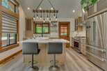 Experience modern rustic charm in this stunning kitchen, featuring a large island with comfortable seating and a unique wooden beam chandelier.