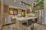 Experience rustic charm in this beautifully appointed kitchen, featuring a large farmhouse sink, a spacious island with granite countertops, and a striking wooden beam light fixture.