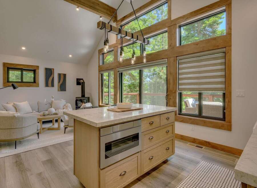 Experience modern mountain living in this stunning open-concept space, featuring a gourmet kitchen island with integrated appliances and ample storage.