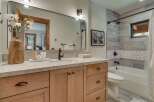 This modern bathroom features a warm wood vanity with ample storage and a sleek quartz countertop.