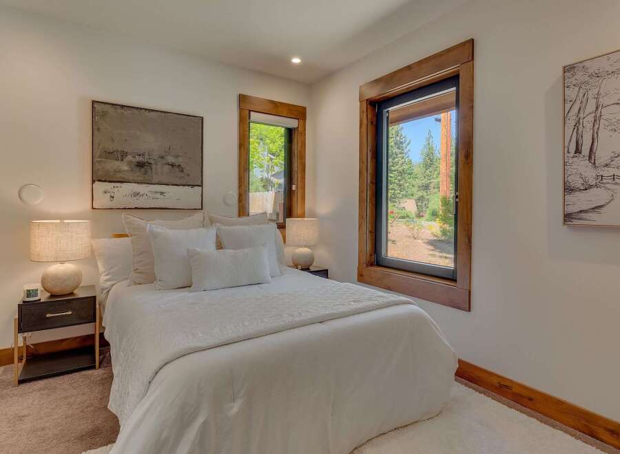 Experience serene mountain living in this beautifully appointed bedroom, featuring a plush white duvet and an abundance of natural light.