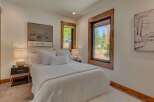 Experience serene mountain living in this beautifully appointed bedroom, featuring a plush white duvet and an abundance of natural light.