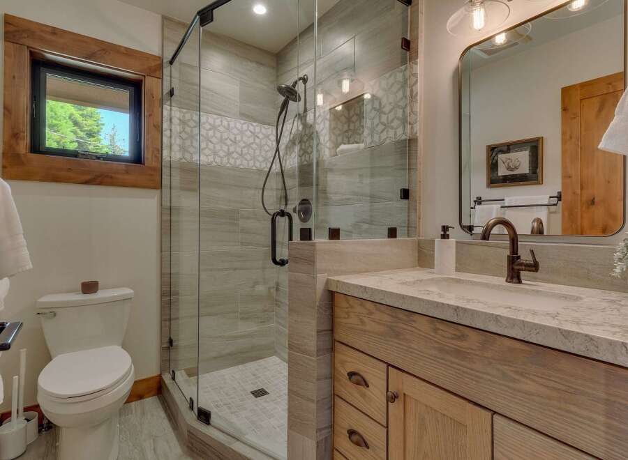 Experience luxury in this modern bathroom featuring a spacious glass-enclosed shower with elegant tile work and a sleek rainfall showerhead.