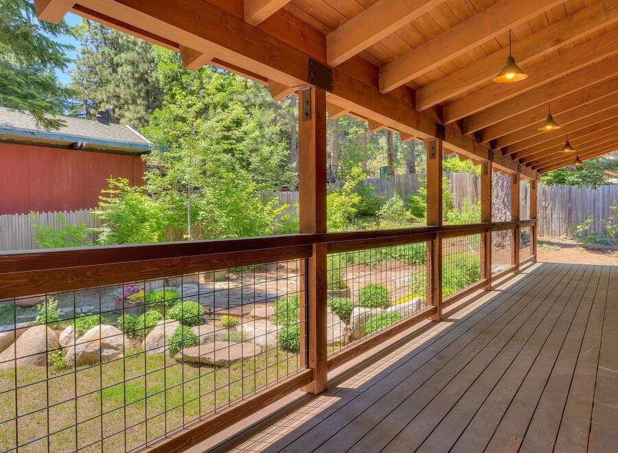 Enjoy the outdoors from this charming covered porch, featuring a rustic wooden deck and ceiling with exposed beams.