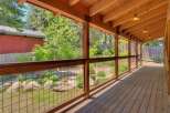 Enjoy the outdoors from this charming covered porch, featuring a rustic wooden deck and ceiling with exposed beams.