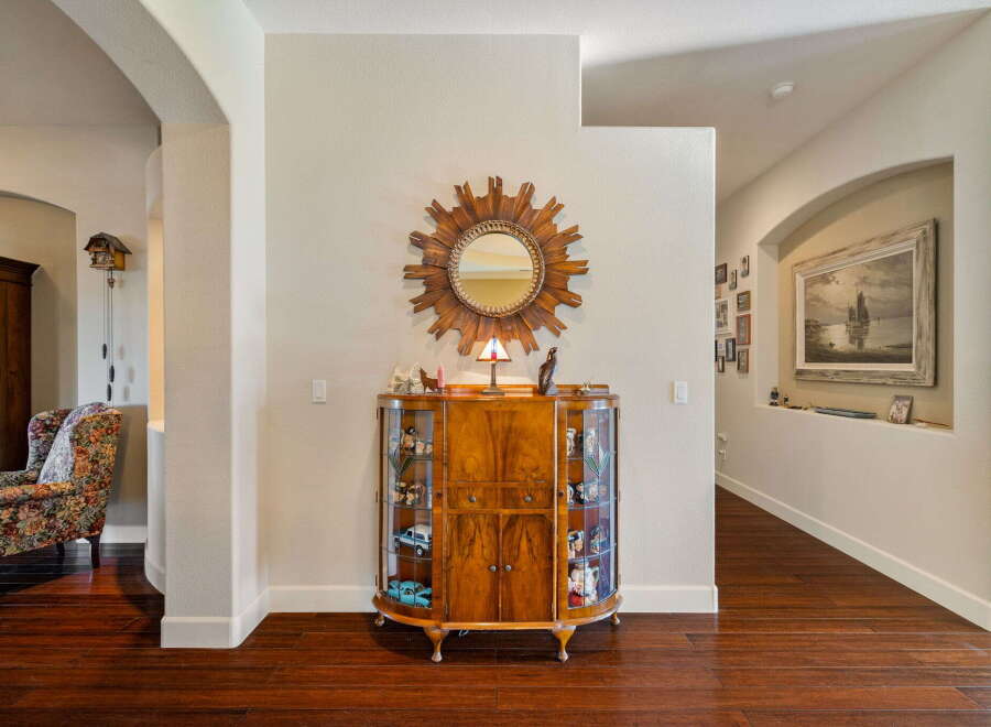 Step into this inviting entryway featuring a charming display cabinet filled with collectibles and a decorative sunburst mirror.