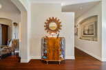 Step into this inviting entryway featuring a charming display cabinet filled with collectibles and a decorative sunburst mirror.