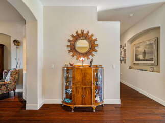 Step into this inviting entryway featuring a charming display cabinet filled with collectibles and a decorative sunburst mirror.