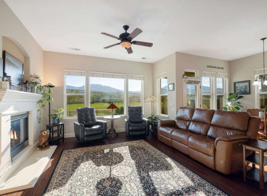 Experience breathtaking mountain views from this stunning living room, featuring a cozy fireplace and comfortable leather seating.