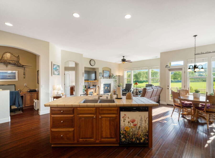 This spacious open-concept kitchen and living area features a large island with a double sink and a decorative dishwasher, perfect for entertaining.