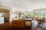 This spacious open-concept kitchen and living area features a large island with a double sink and a decorative dishwasher, perfect for entertaining.