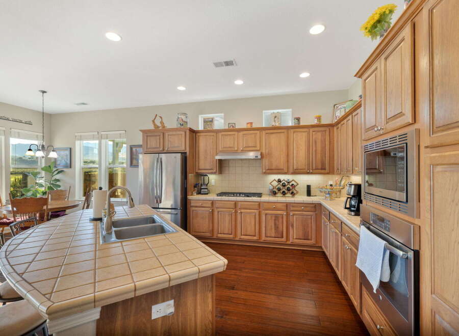 This spacious kitchen boasts beautiful oak cabinetry and a large tiled island with a double sink, perfect for meal preparation and entertaining.