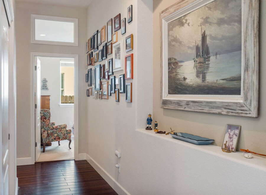 This hallway features a striking gallery wall with a diverse collection of framed photos and artwork, adding a personal touch to the space.