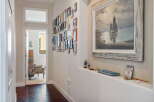 This hallway features a striking gallery wall with a diverse collection of framed photos and artwork, adding a personal touch to the space.