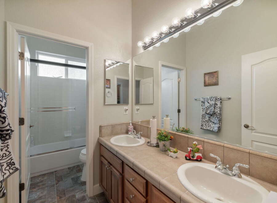 This bright bathroom features a spacious vanity with dual sinks and ample counter space, perfect for busy mornings.