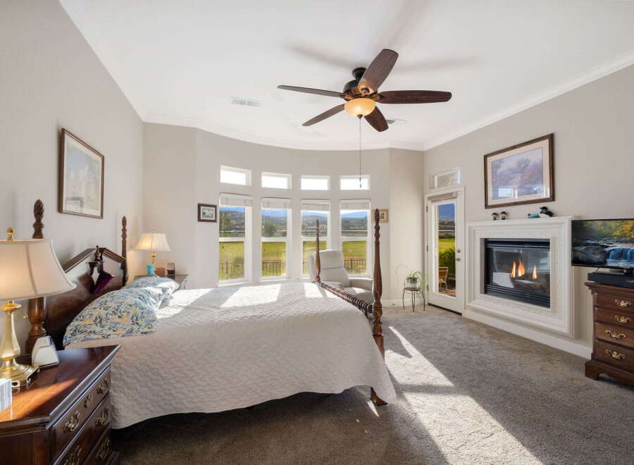 Experience luxury and comfort in this stunning master bedroom, featuring a grand four-poster bed and a cozy fireplace perfect for chilly evenings.