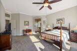 Experience luxurious living in this spacious master suite, featuring a grand four-poster bed and elegant wooden furniture.