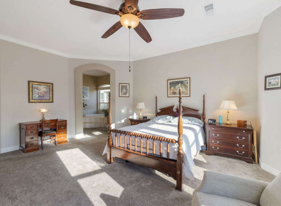 Experience luxury and comfort in this spacious master suite, featuring a grand four-poster bed and a cozy seating area.