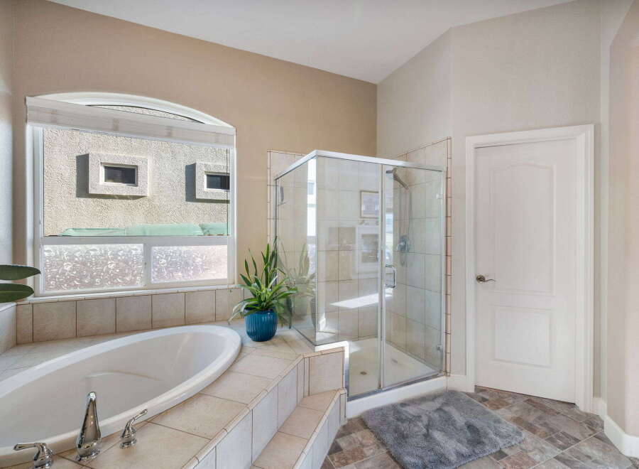 Indulge in luxury with this stunning bathroom featuring a spacious corner soaking tub and a separate glass-enclosed shower.