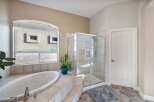 Indulge in luxury with this stunning bathroom featuring a spacious corner soaking tub and a separate glass-enclosed shower.