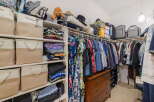 Discover ample storage solutions in this spacious walk-in closet, featuring a variety of shelving, fabric bins, and a charming antique dresser.