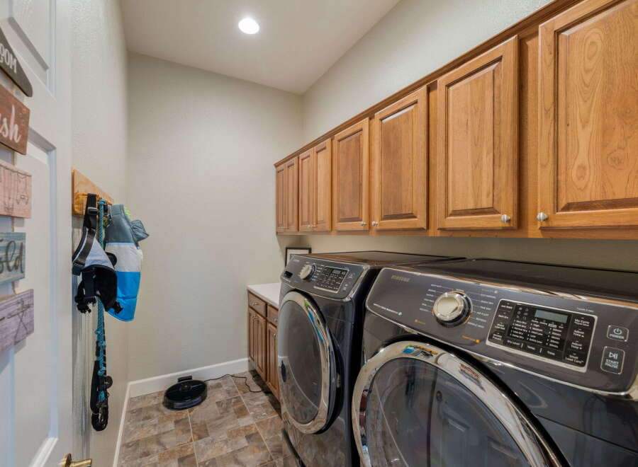 This laundry room boasts ample storage with beautiful wooden cabinets lining the walls, perfect for organizing all your laundry essentials.