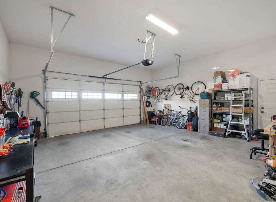 This spacious garage offers ample storage solutions, including a tall shelving unit and a filing cabinet, perfect for organizing tools and equipment.
