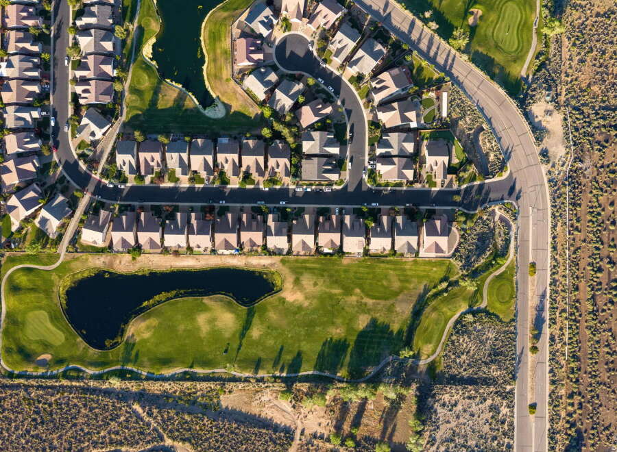 Experience luxury living in this stunning aerial view of a master-planned community, featuring a pristine golf course with a serene water feature.
