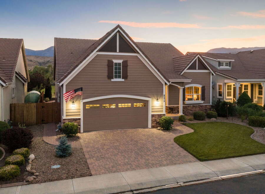 This stunning home features a beautifully landscaped front yard with a lush green lawn and mature shrubs, leading to a welcoming entryway.