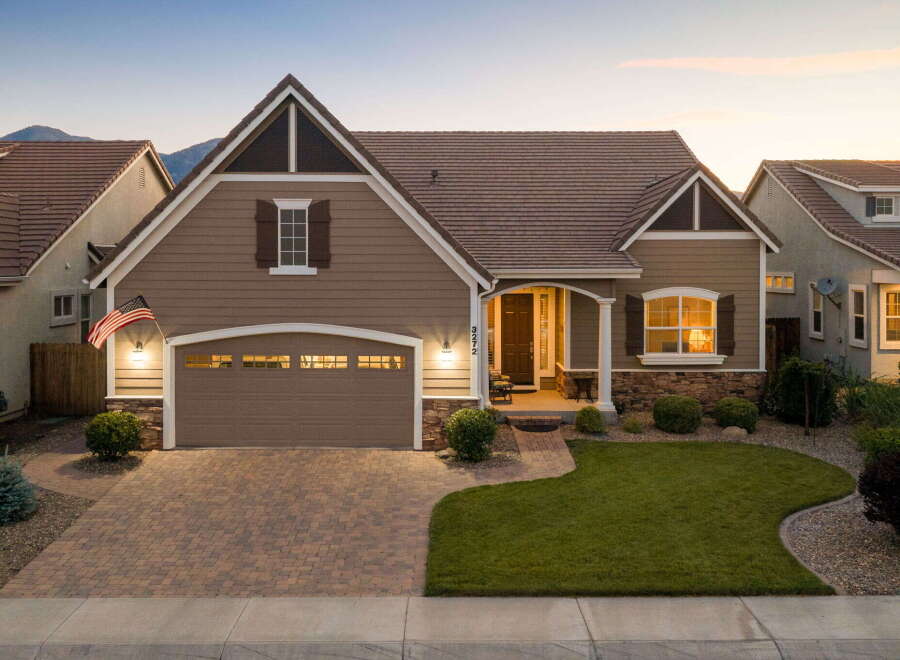 This charming single-family home features a welcoming facade with a well-maintained lawn and a paved driveway leading to an attached garage.