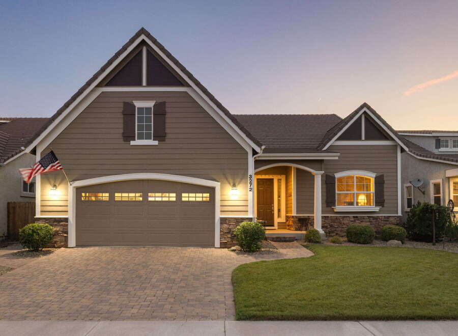 This charming home features a welcoming facade with a well-maintained lawn and a paved driveway leading to an attached garage.