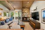 Experience cozy mountain living in this inviting living room, featuring a striking stone fireplace and a vaulted wood-beamed ceiling.