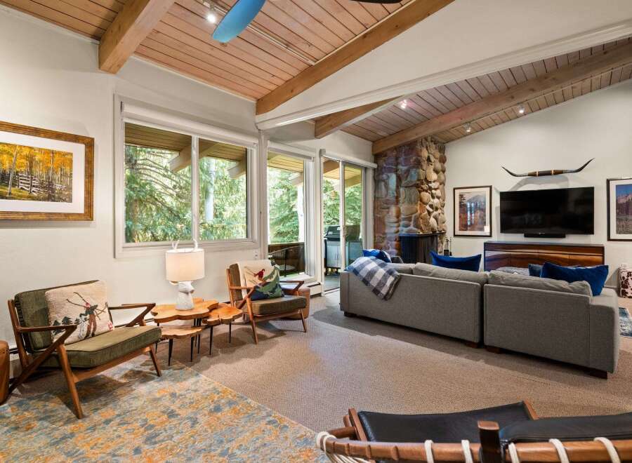 Experience rustic charm in this inviting living room, featuring a striking stone fireplace and exposed wooden beams that create a warm, cabin-like ambiance.