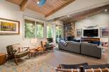 Experience rustic charm in this inviting living room, featuring a striking stone fireplace and exposed wooden beams that create a warm, cabin-like ambiance.