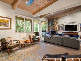 Experience rustic charm in this inviting living room, featuring a striking stone fireplace and exposed wooden beams that create a warm, cabin-like ambiance.