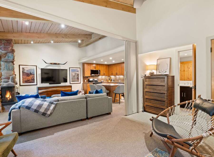 Experience rustic charm in this inviting living space, featuring a grand stone fireplace and exposed wooden beams that create a warm, cozy atmosphere.