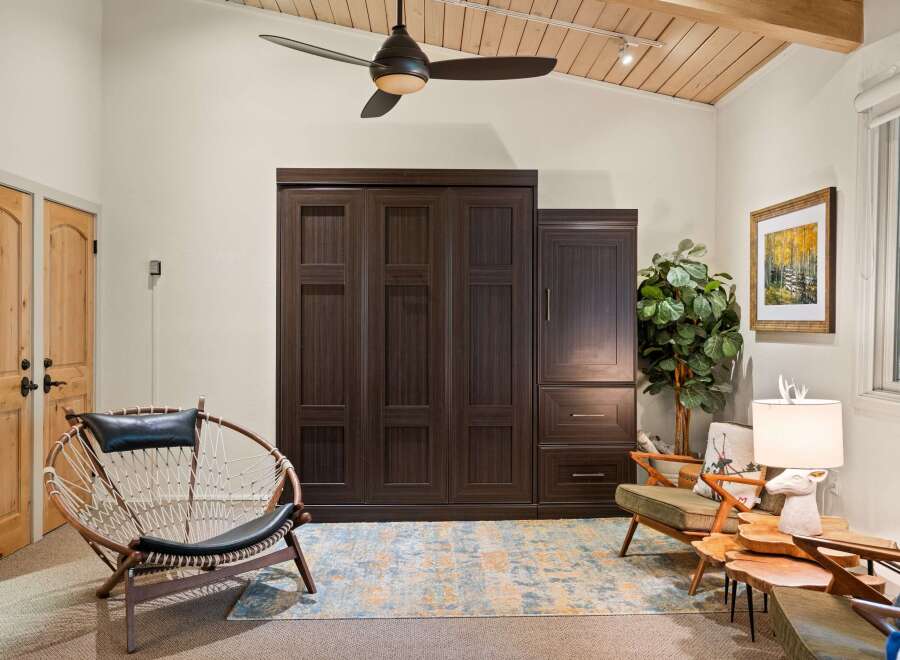 Discover this inviting living space featuring a large, dark wood murphy bed system, perfect for maximizing room utility.