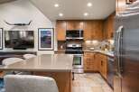 This modern kitchen boasts beautiful natural wood cabinetry complemented by a sleek stainless steel appliance suite, including a microwave, oven, and refrigerator.