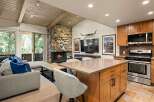 Experience rustic charm in this open-concept living space, featuring a striking stone fireplace and a vaulted wood-beamed ceiling.