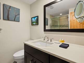 This modern bathroom features a sleek vanity with a white undermount sink and chrome fixtures, complemented by a large dark-framed mirror.